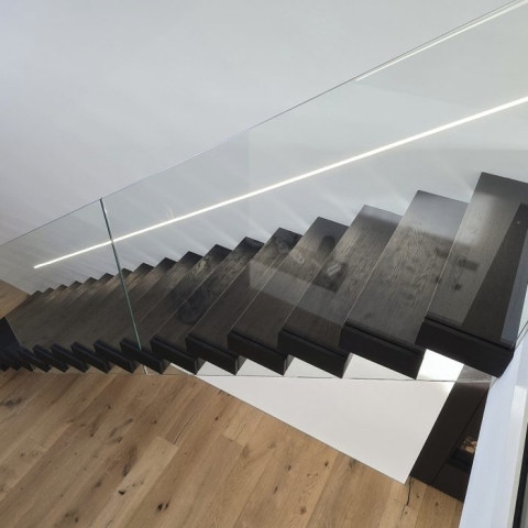 Kragarmtreppe mit Balustrade aus gehärtetem Glas. Schwarzes Eichenholz. Glasgelander.